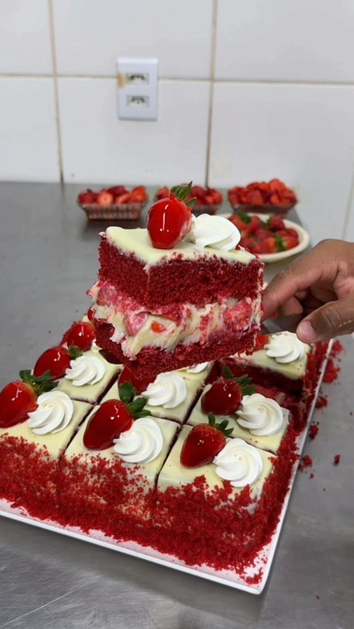 Red velvet cake slices with white frosting and glazed cherries on a tray.