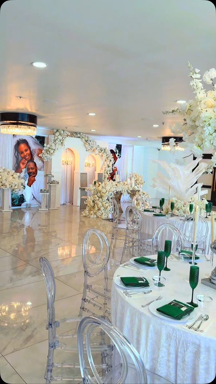 Elegant party setup with white floral arches, round tables, and a couple's portrait.