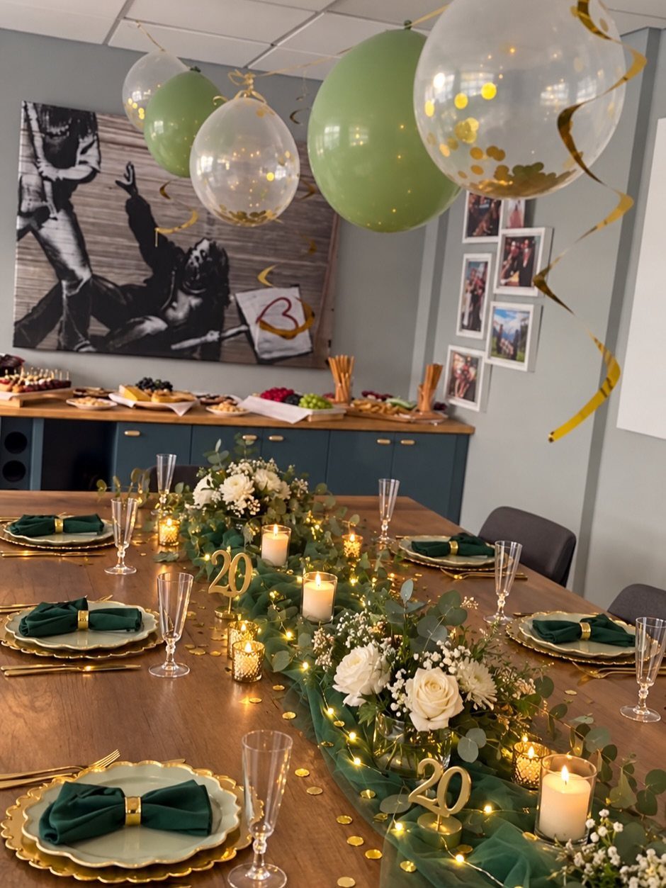 Decorated dining table with green and gold theme, white roses, and gold 20 numbers.