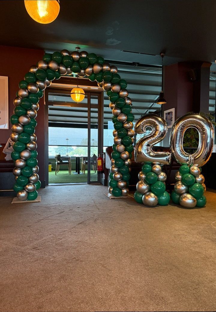 Green and silver balloon arch and silver number 20 balloons for an anniversary party.