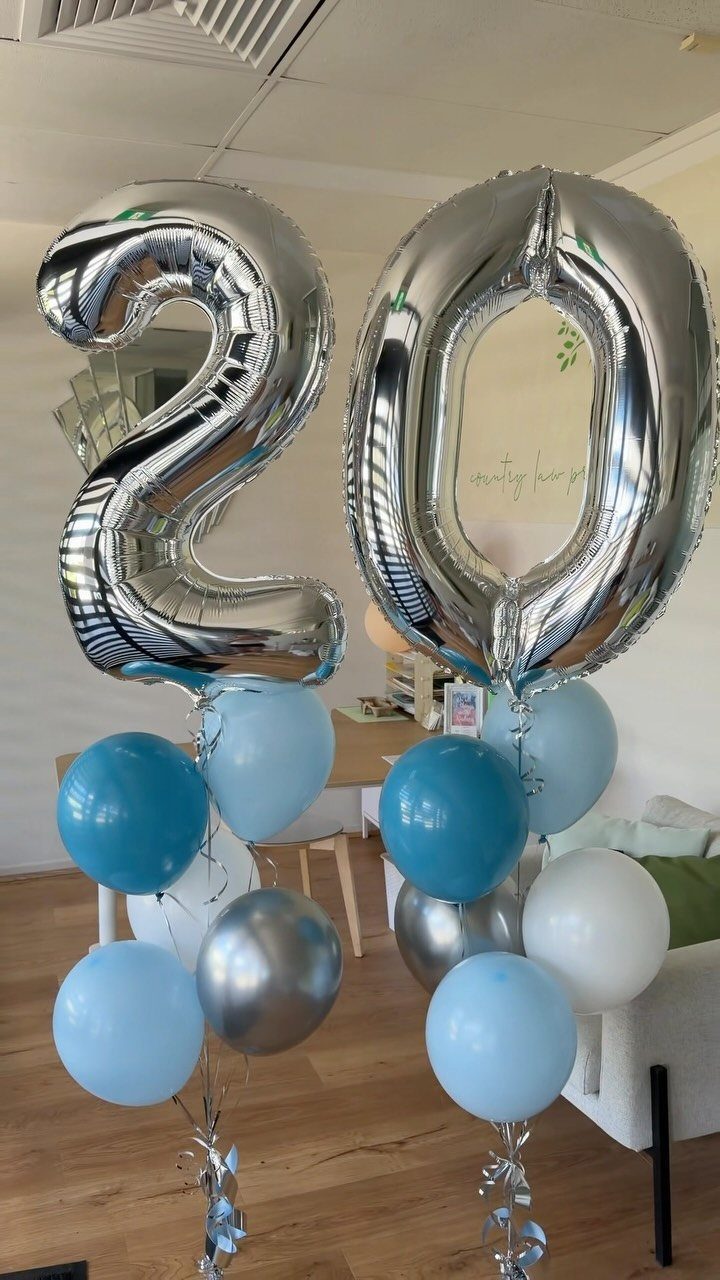 Silver number 20 foil balloons with blue and white balloons in a room.