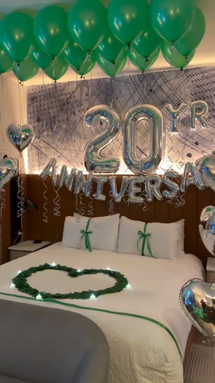 Bed decorated with green balloons and silver anniversary balloons for a 20th celebration