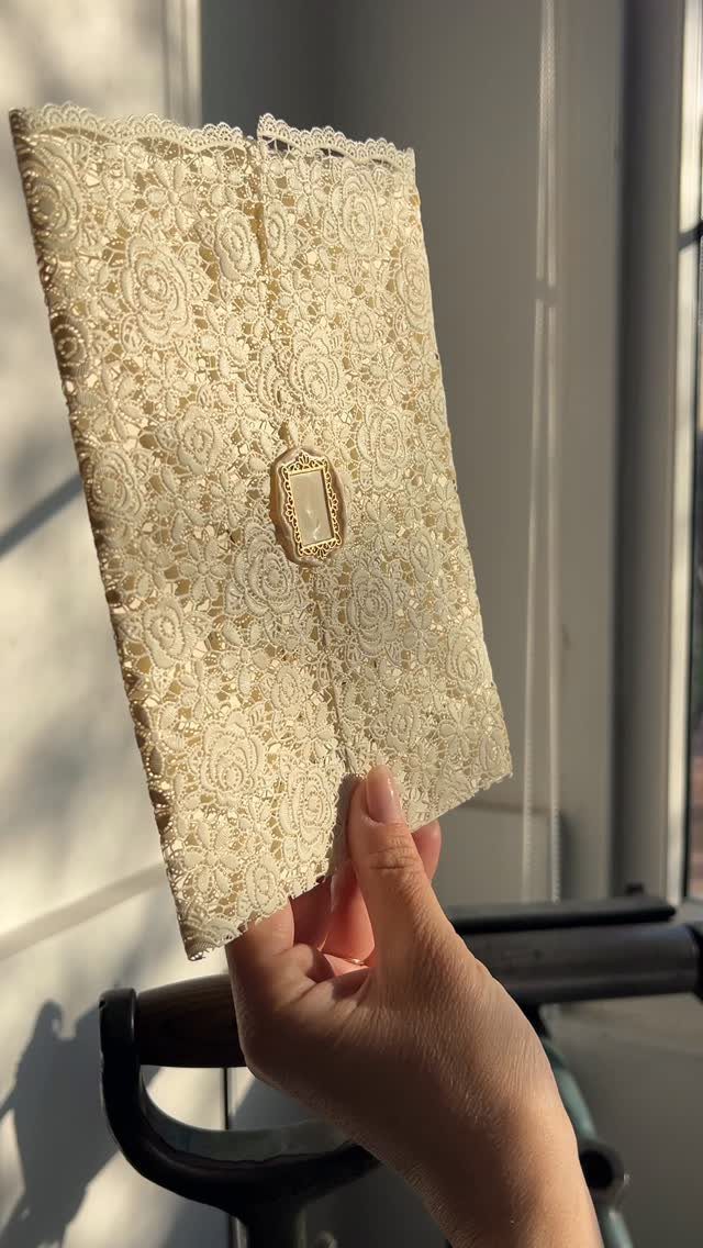 32 Anniversary Card Ideas to Make at Home (Photos Inside) 17 Cream lace fabric card with a gold ornament held by a hand.