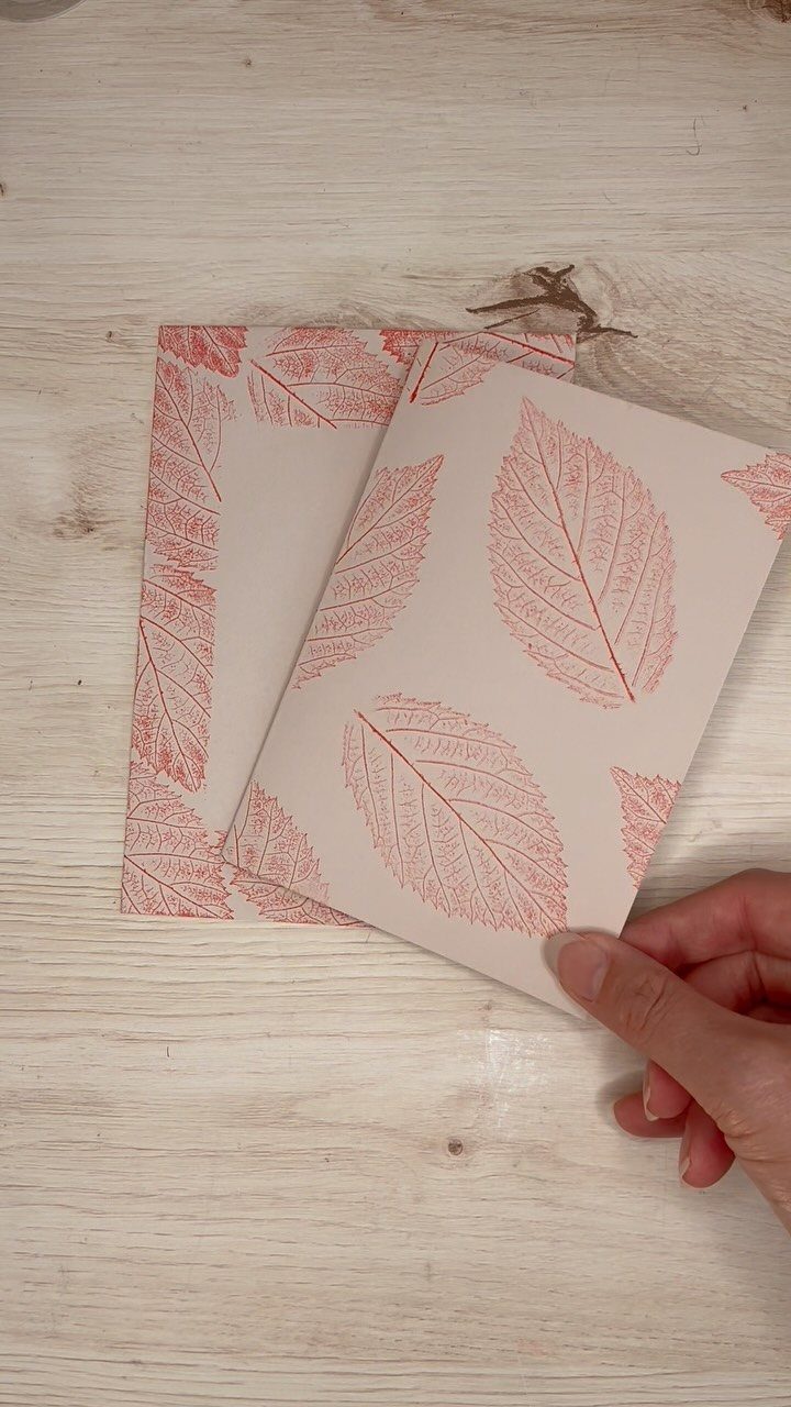 32 Anniversary Card Ideas to Make at Home (Photos Inside) 19 White cards with red leaf prints held by a hand on wooden background