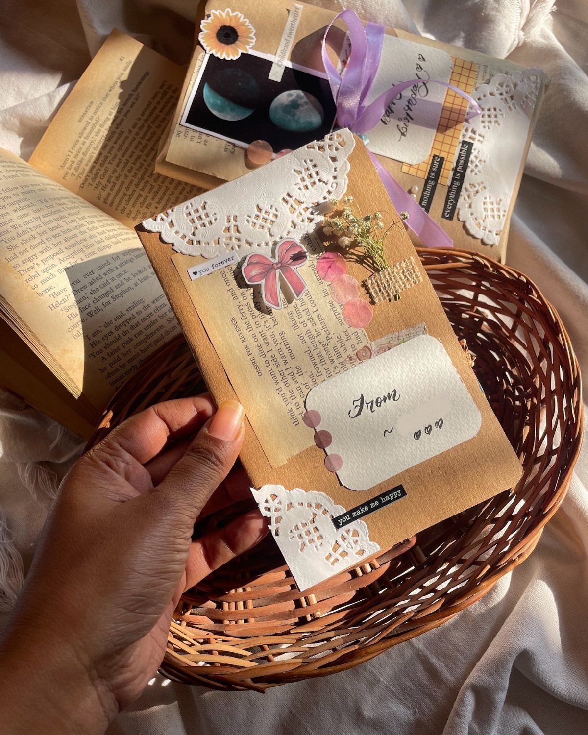 32 Anniversary Card Ideas to Make at Home (Photos Inside) 12 Hand holding a decorated brown kraft envelope with lace and a pink bow.