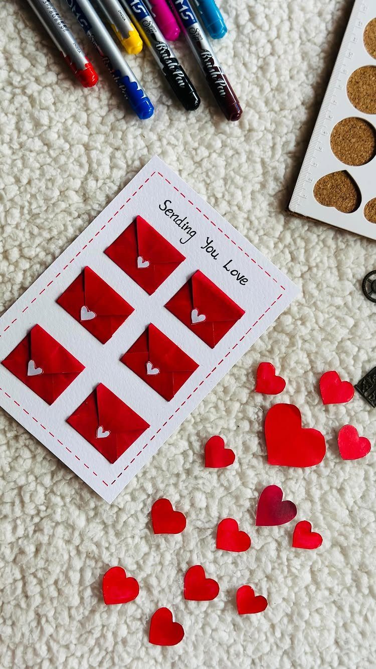 32 Anniversary Card Ideas to Make at Home (Photos Inside) 29 White card with small red envelopes and red paper hearts on a textured surface