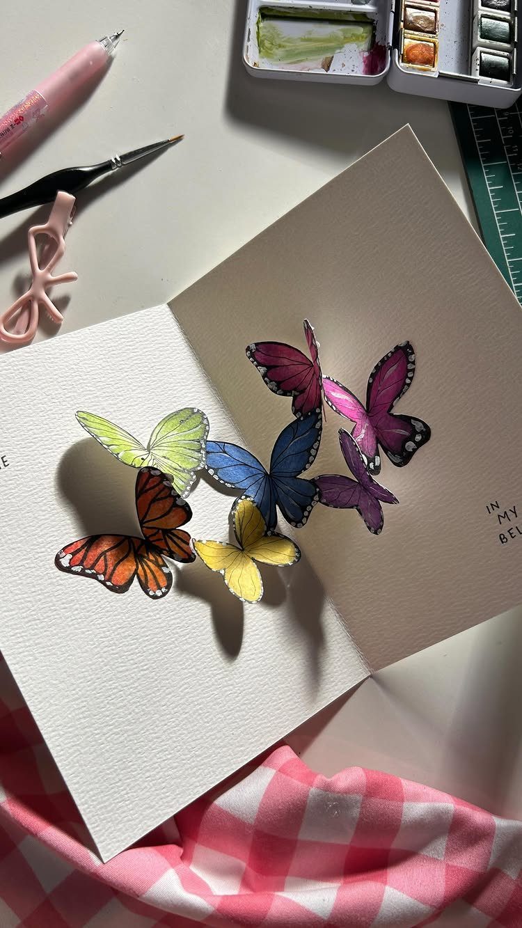 32 Anniversary Card Ideas to Make at Home (Photos Inside) 20 Colorful 3D pop-up butterflies inside an open white greeting card on a desk.