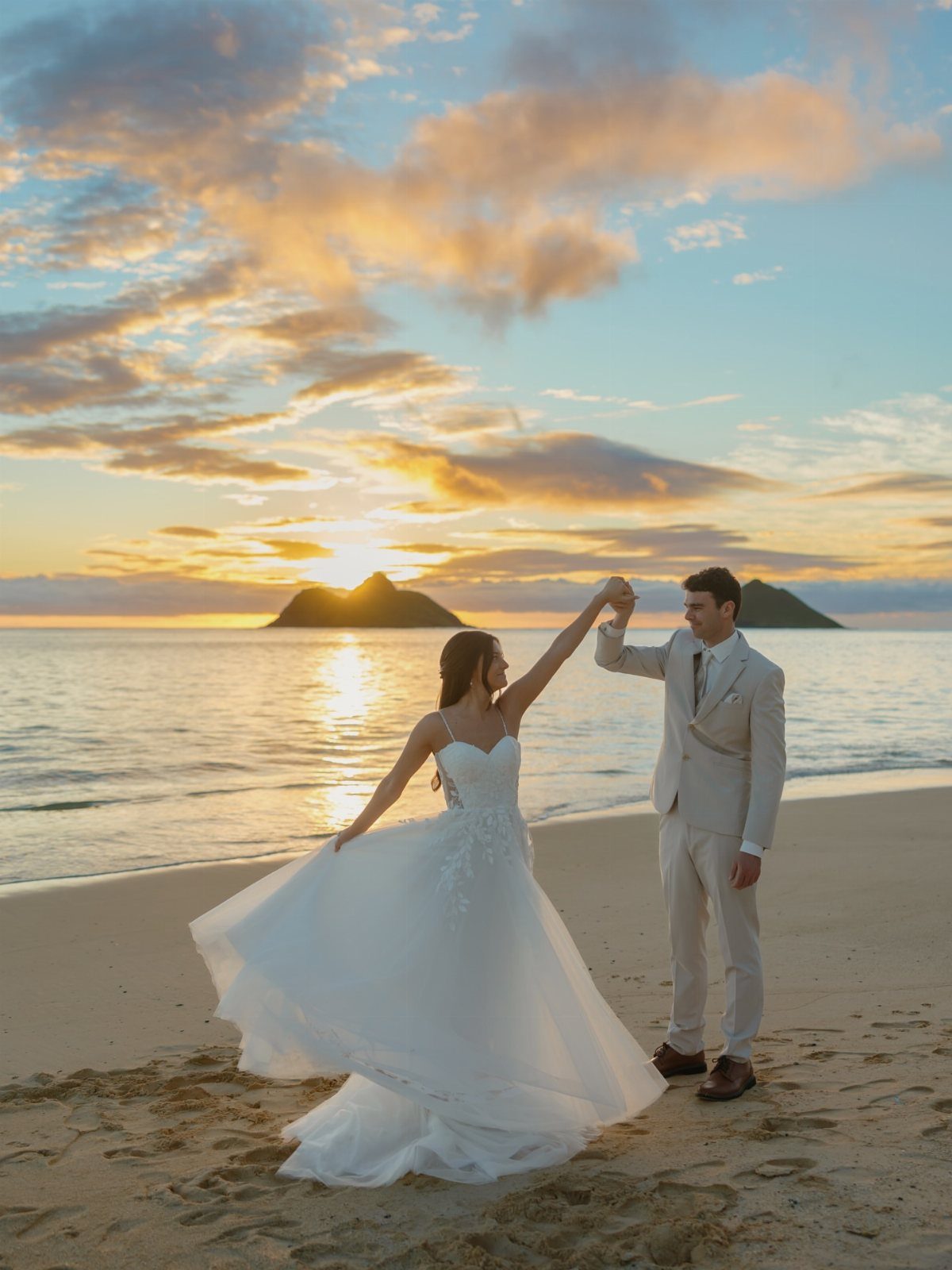 Bride and groom holding hands on a beach during a golden sunset.
