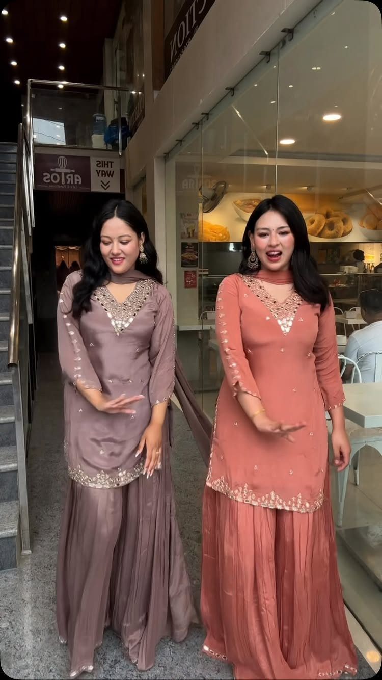 Two women wearing elegant mauve and peach traditional Indian salwar kameez outfits.