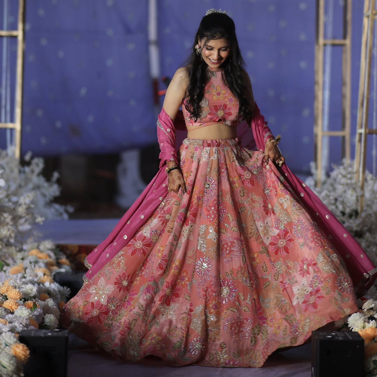 Woman wearing a pink and orange floral print lehenga with a matching dupatta.