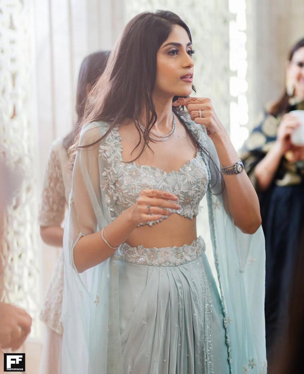 Woman in a sea green embellished lehenga set with a sheer dupatta.