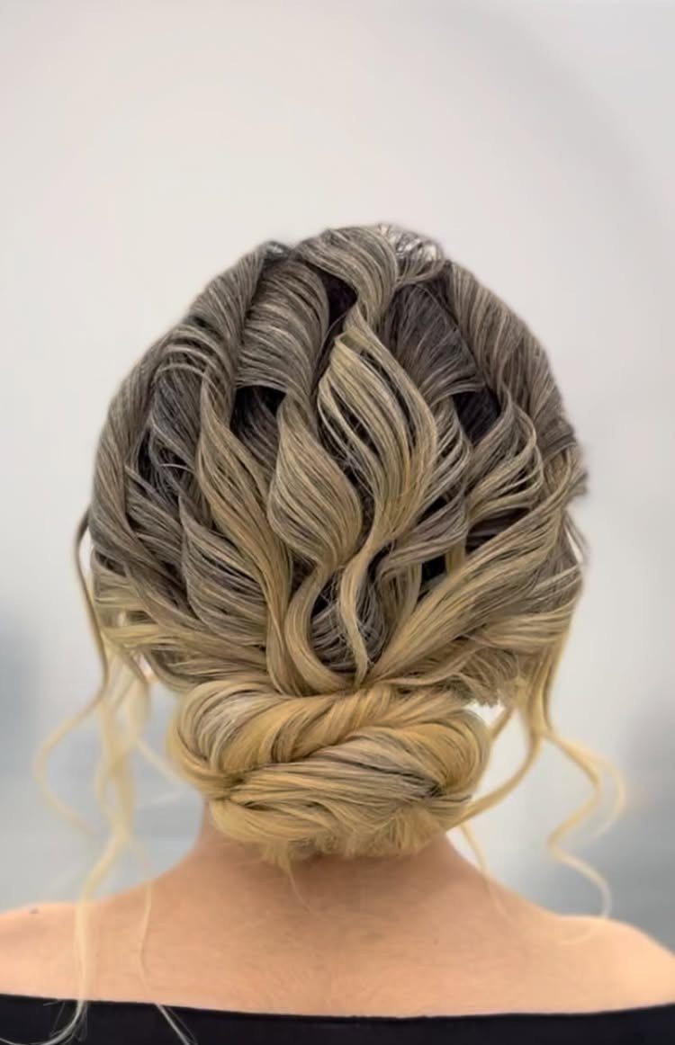Blonde and brown balayage curly hair styled in a voluminous low bridal bun updo.