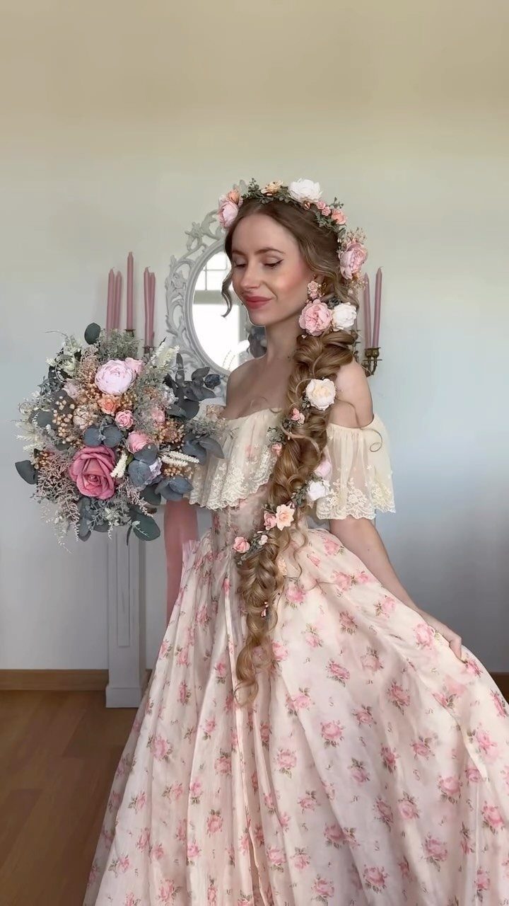 Woman with a long curly side braid and flower crown wearing a floral gown.