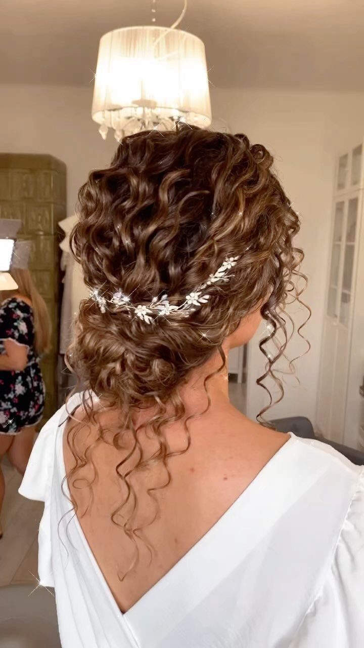 Brown curly hair styled in a wedding updo with a silver leaf accessory.