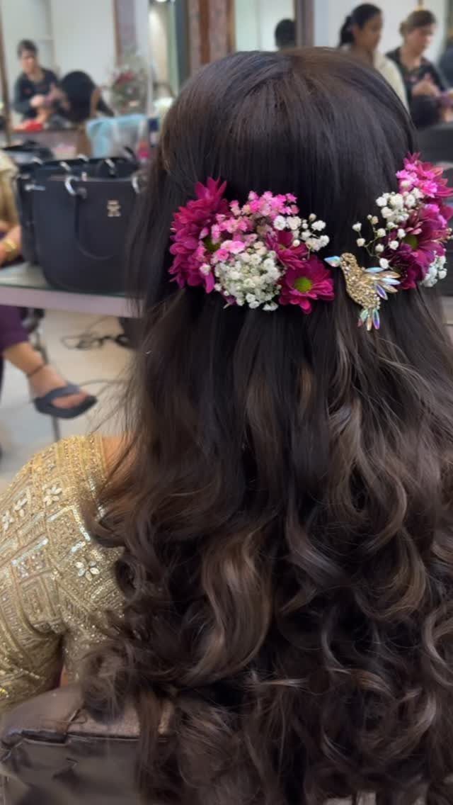 Long dark brown curly hair adorned with pink and white flowers and a gold bird.
