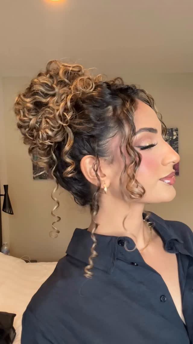 Woman with curly brown hair styled in a high, elegant wedding updo.
