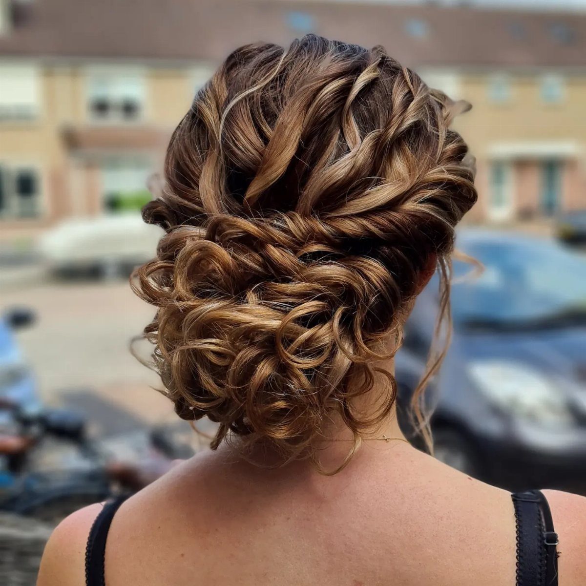 Intricate curly hair wedding updo with blonde highlights on a person's head.