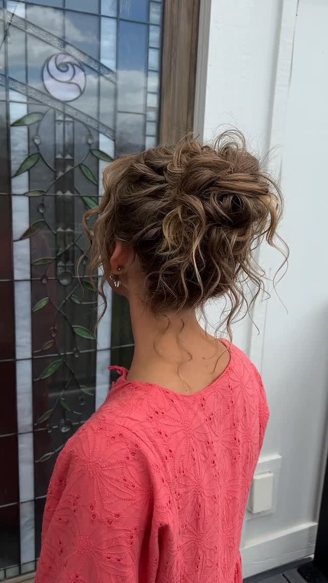 Woman with light brown curly hair styled in a loose, textured wedding updo.