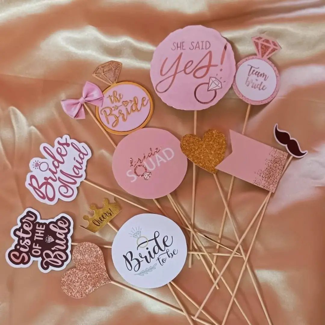 Wedding photo booth props with bridal text and shapes on gold satin fabric.