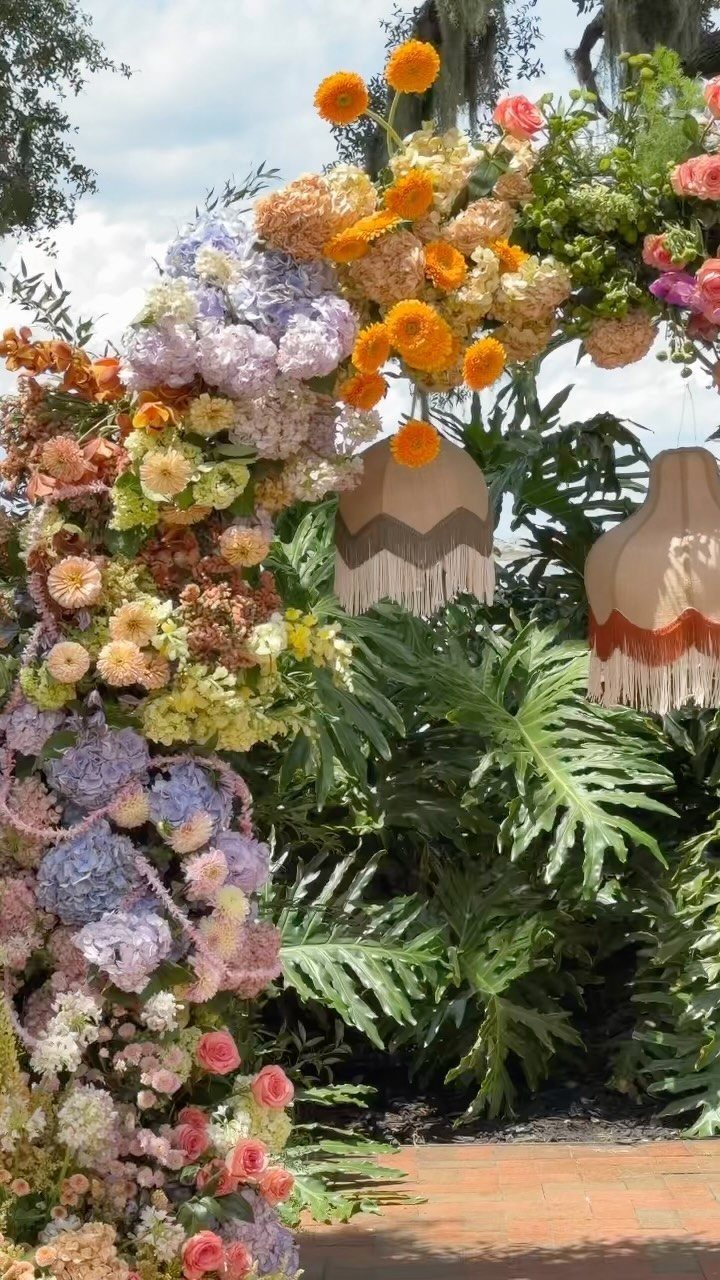 Floral arch with colorful blooms and tropical greenery in an outdoor setting.