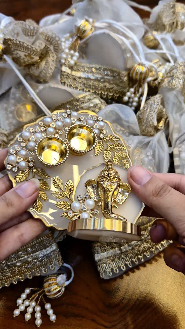 Ornate gold Ganesha tray with pearls and small bowls held by hands.