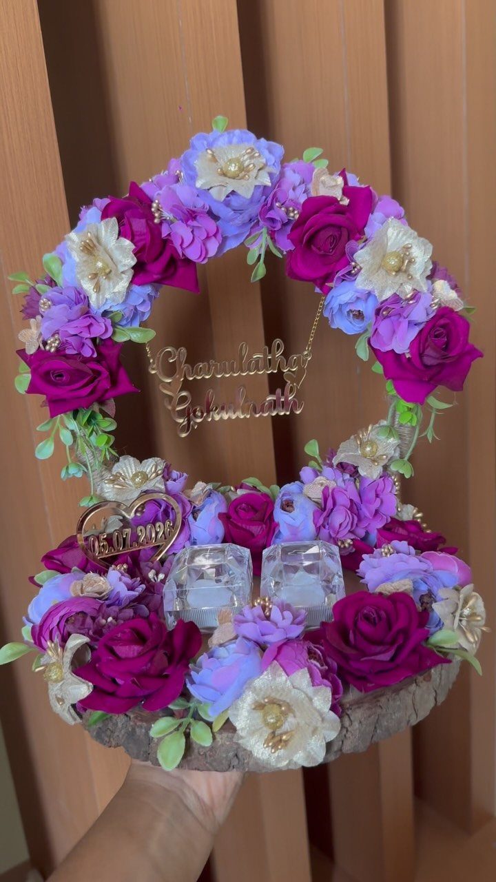 Pink and purple floral ring platter with a gold nameplate and ring boxes.