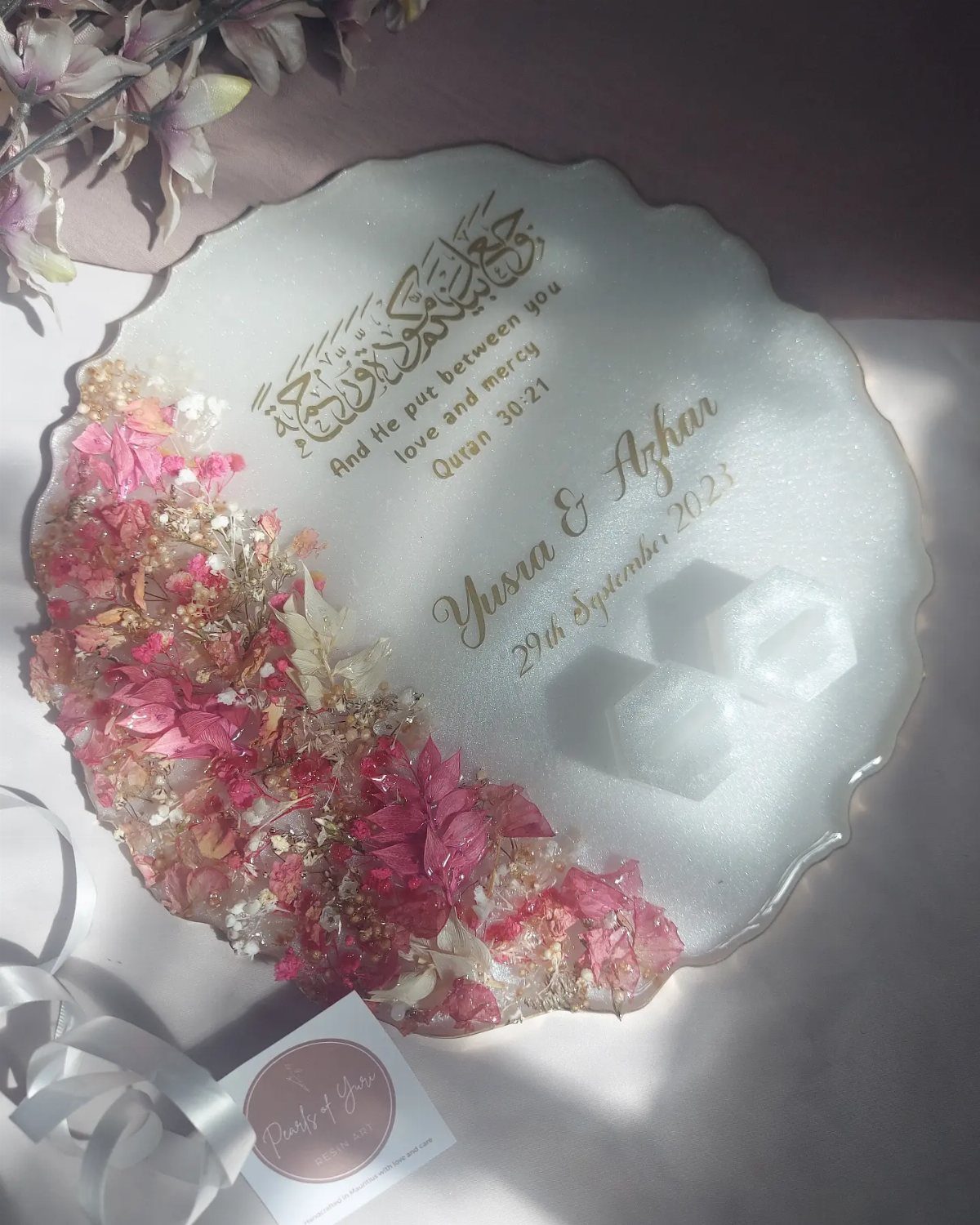 White resin engagement platter with pink dried flowers and gold calligraphy names.