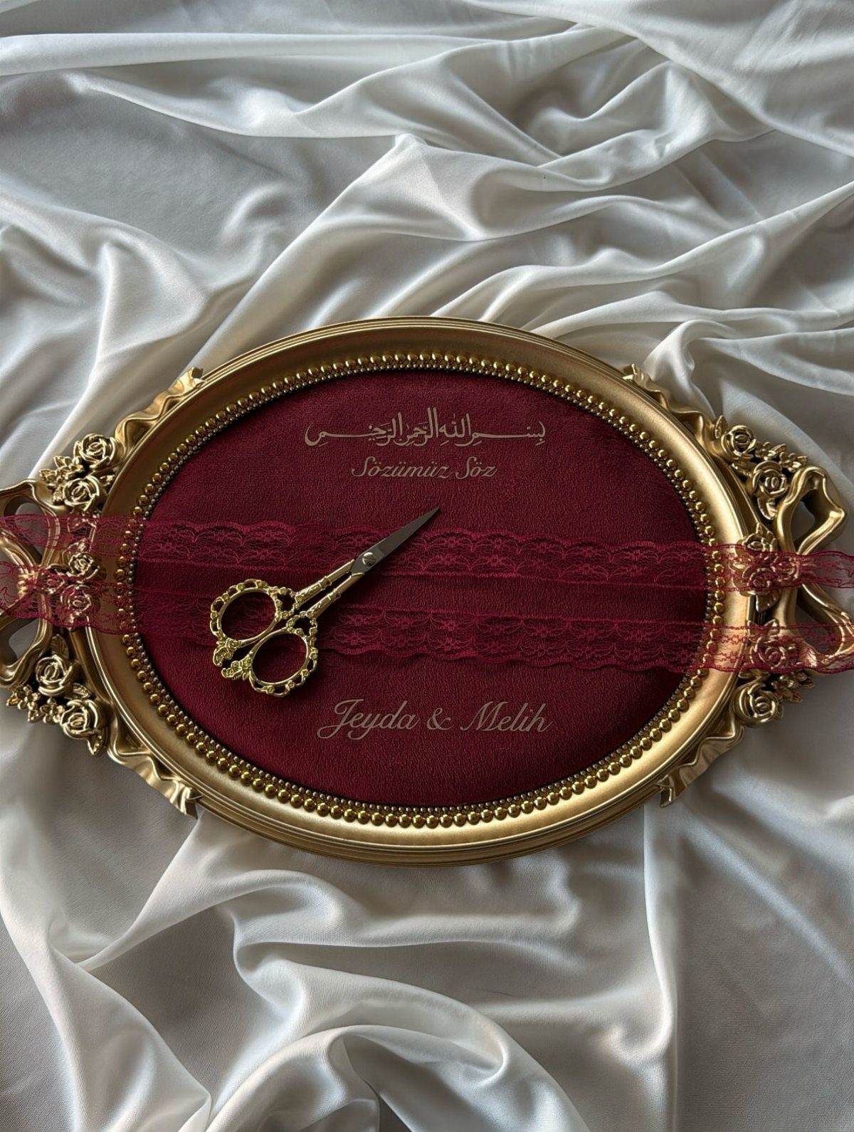 Gold oval platter with red velvet padding, gold scissors, and red lace ribbon.