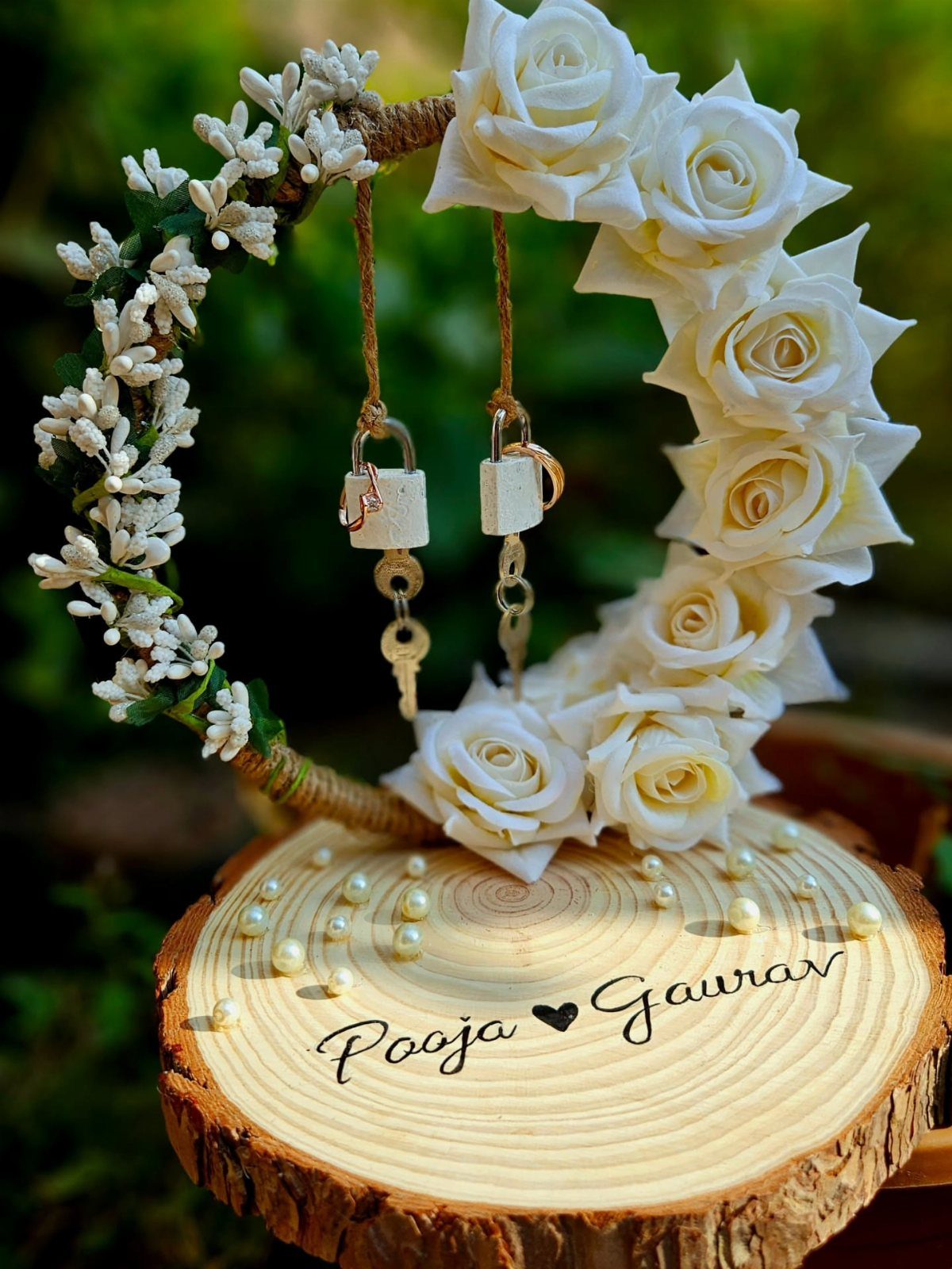 Wooden slice platter with engraved names and pearls beside a floral heart hoop.