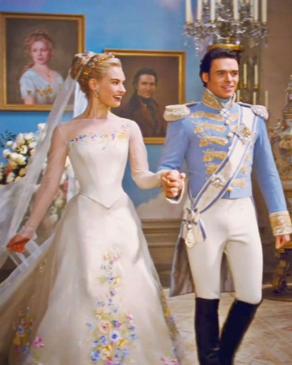 Woman in floral white wedding gown and man in blue military uniform posing together.