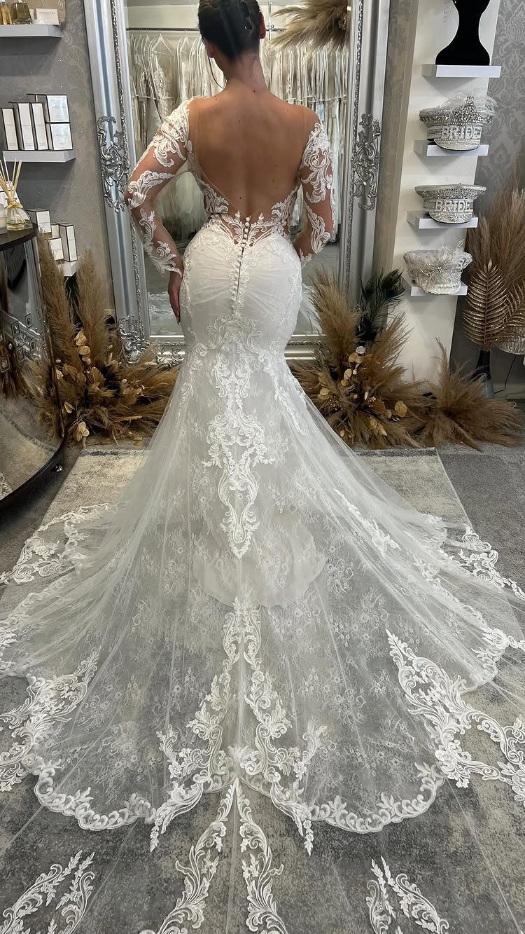 White lace mermaid wedding dress with a long ornate train and deep V-back.