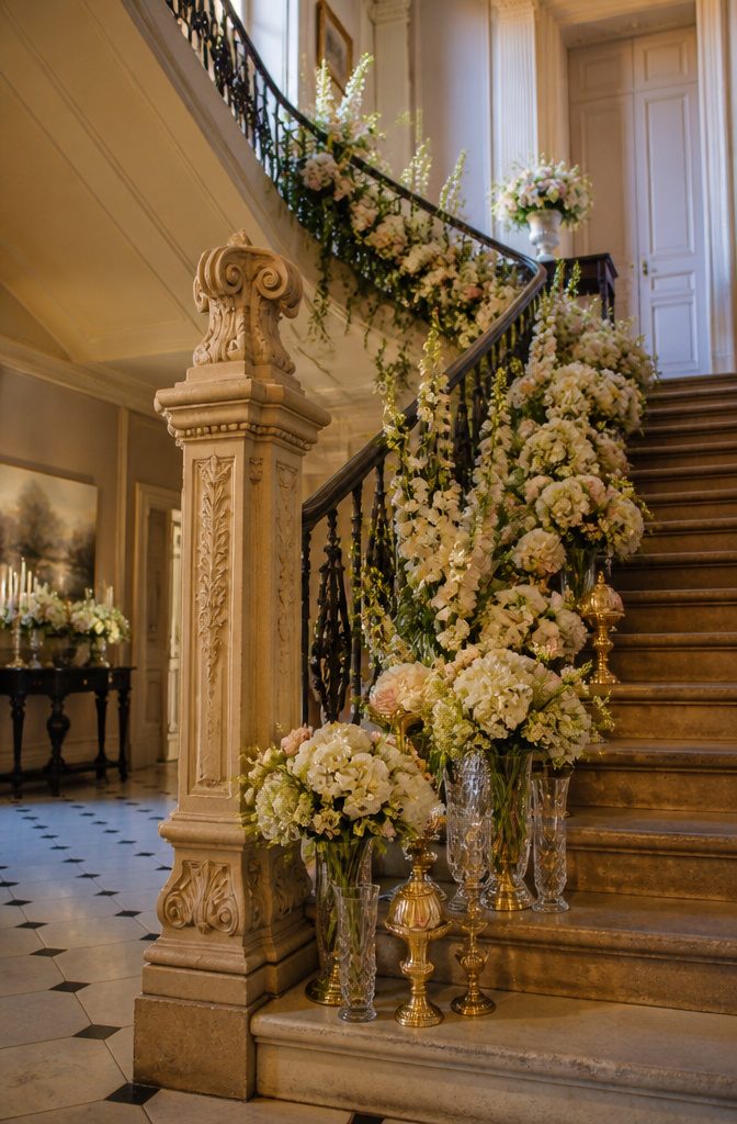 Staircase railing wrapped with cascading wedding flowers and greenery