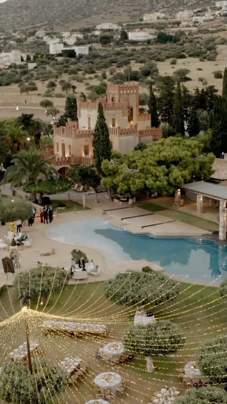 Luxury estate with castle architecture, swimming pool, and outdoor event lighting and tables.