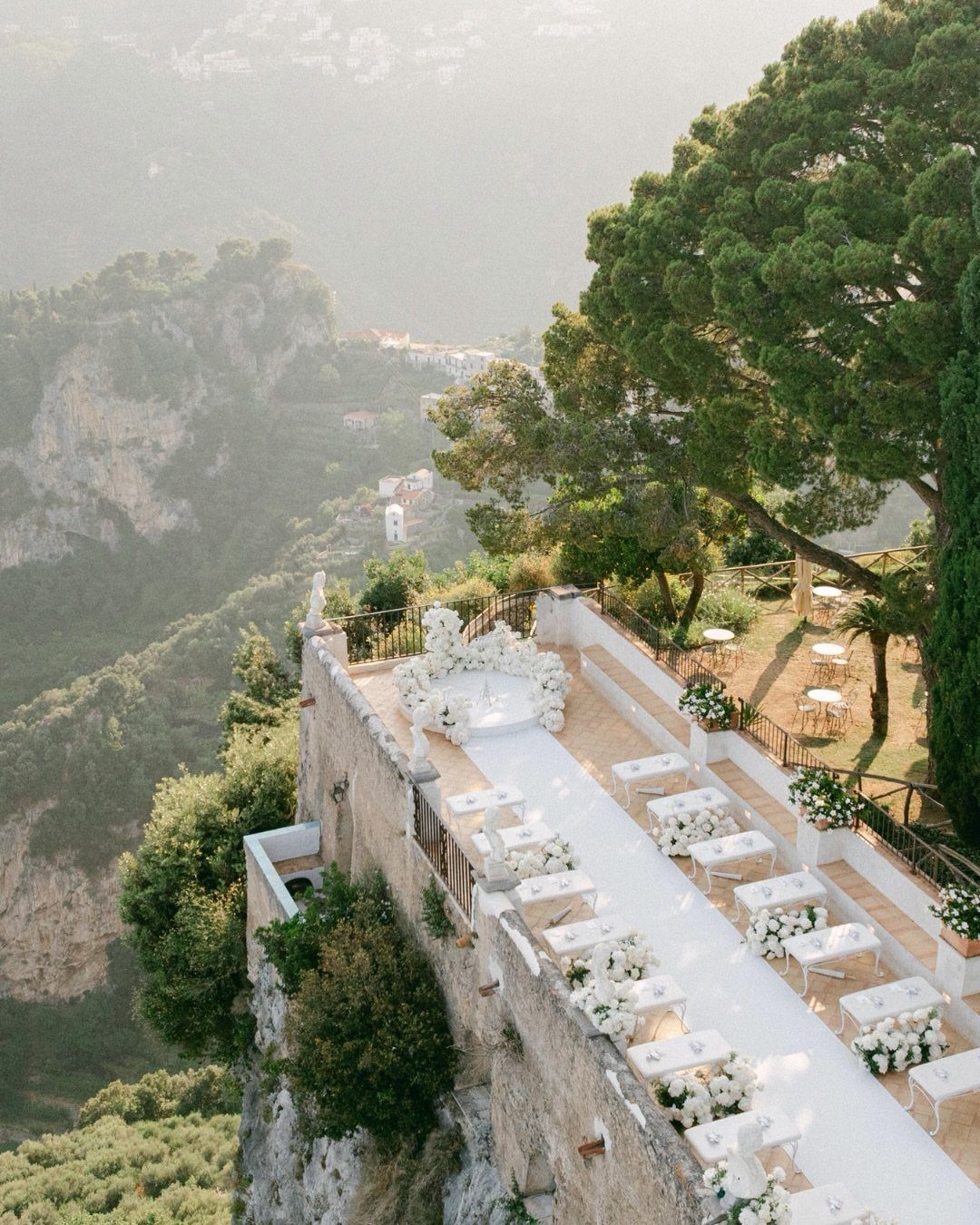 Wedding ceremony setup on a stone terrace overlooking a lush green valley.