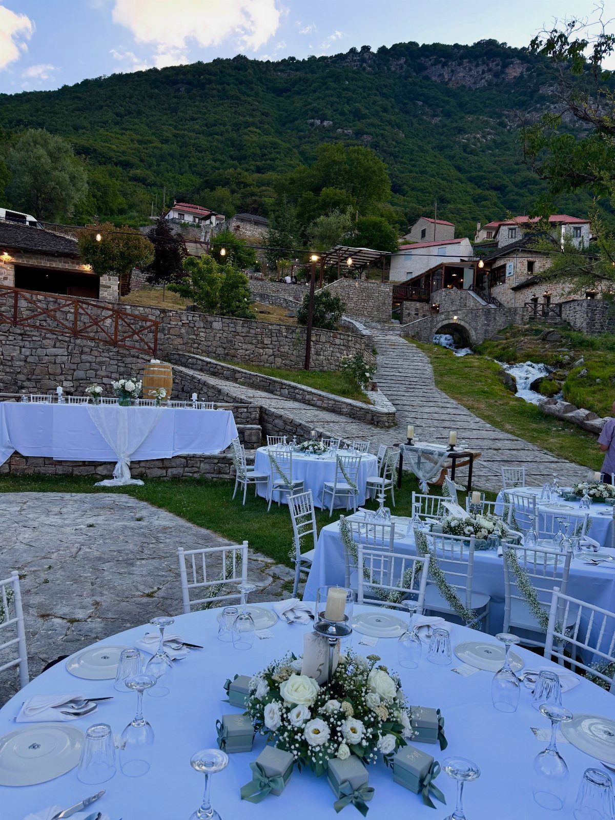 Wedding reception tables with white linens and flowers set against a mountain village.
