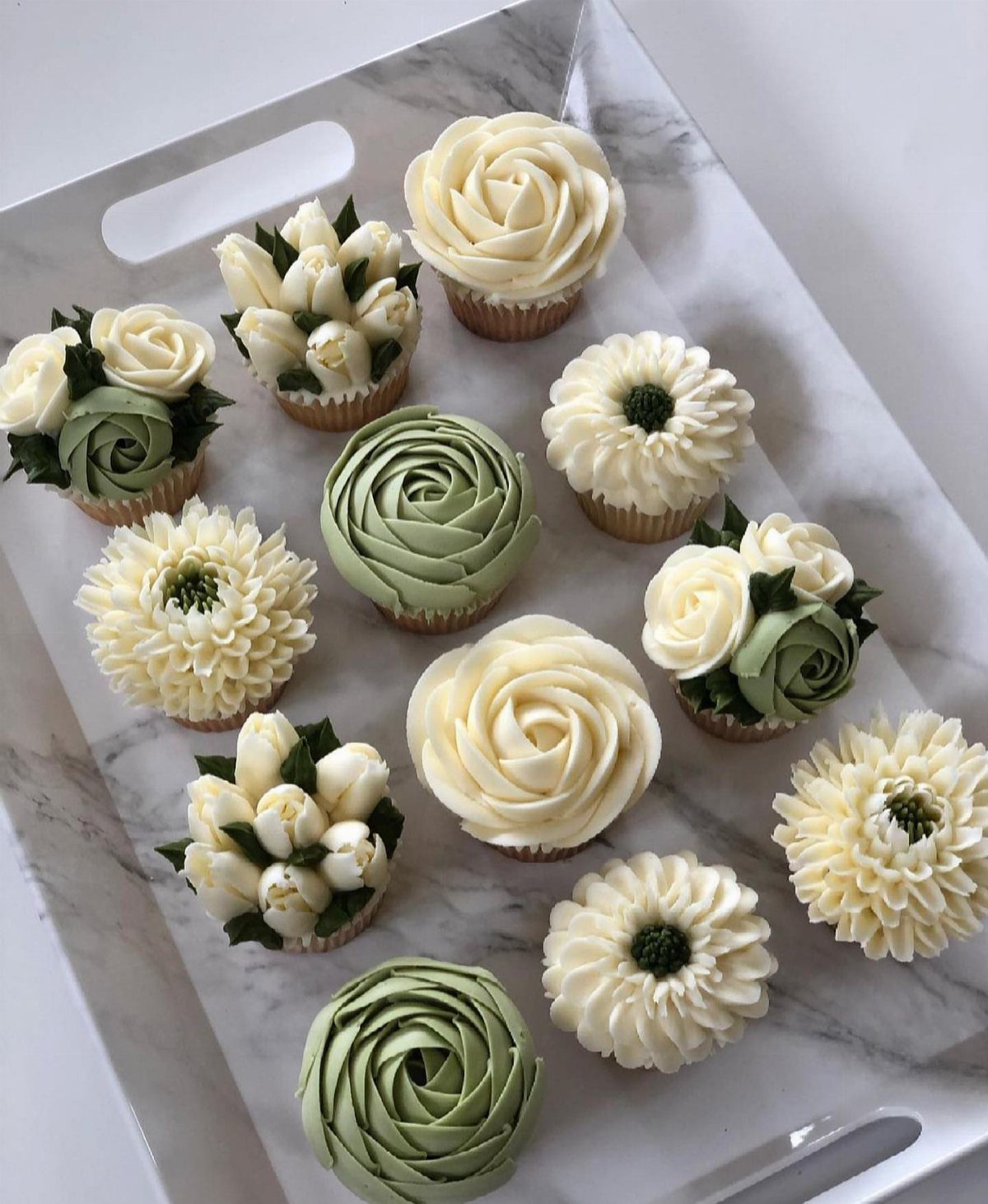 Green Bridal Shower Ideas: 10 Eco-Friendly Party Picks 11 Cupcakes with cream and green floral frosting arranged on a white marble tray.
