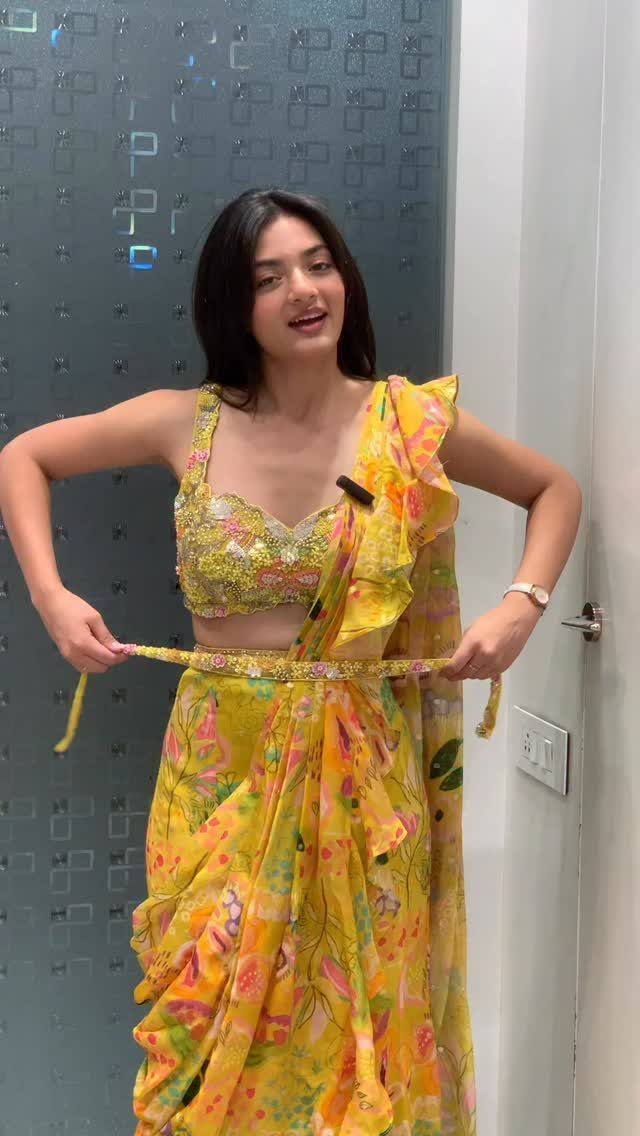 Woman wearing a yellow floral print saree with a matching cropped blouse.