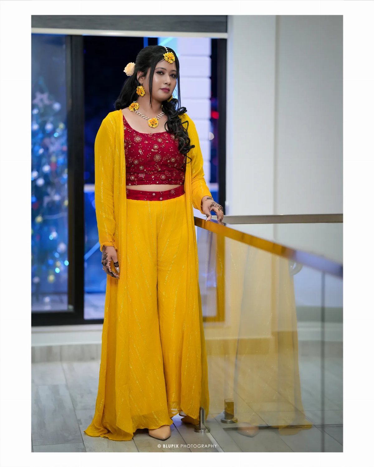 Woman in yellow long jacket, red crop top, and yellow trousers for Haldi.