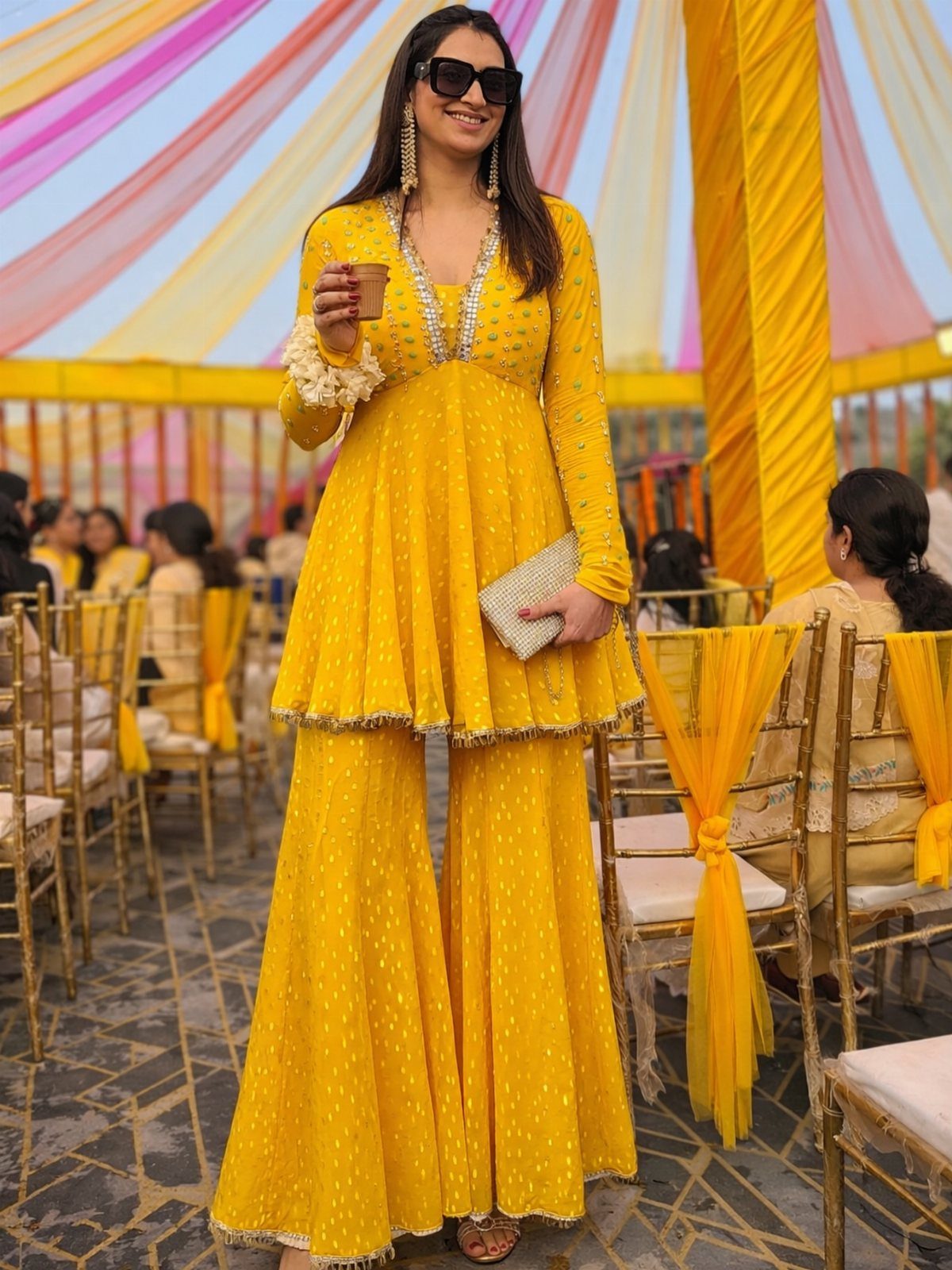 Woman in yellow peplum top and wide-leg lurex pants at a festive event.