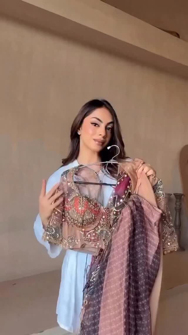Woman holding a heavily embellished saree with gold embroidery and mirror work.