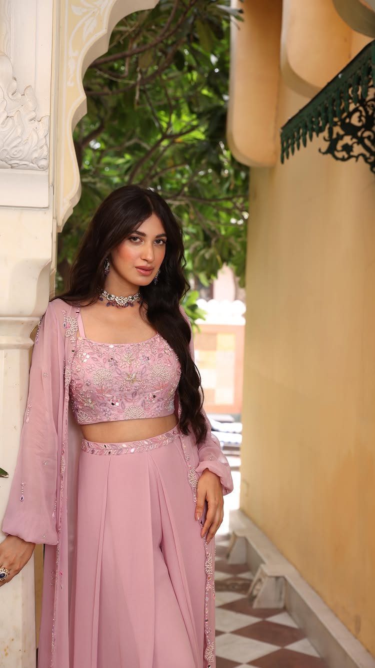 Woman in a light pink pastel embroidered crop top and matching wide-leg trousers.