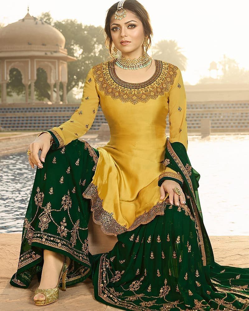 Woman in yellow embroidered tunic and dark green wide-legged trousers with gold detailing.
