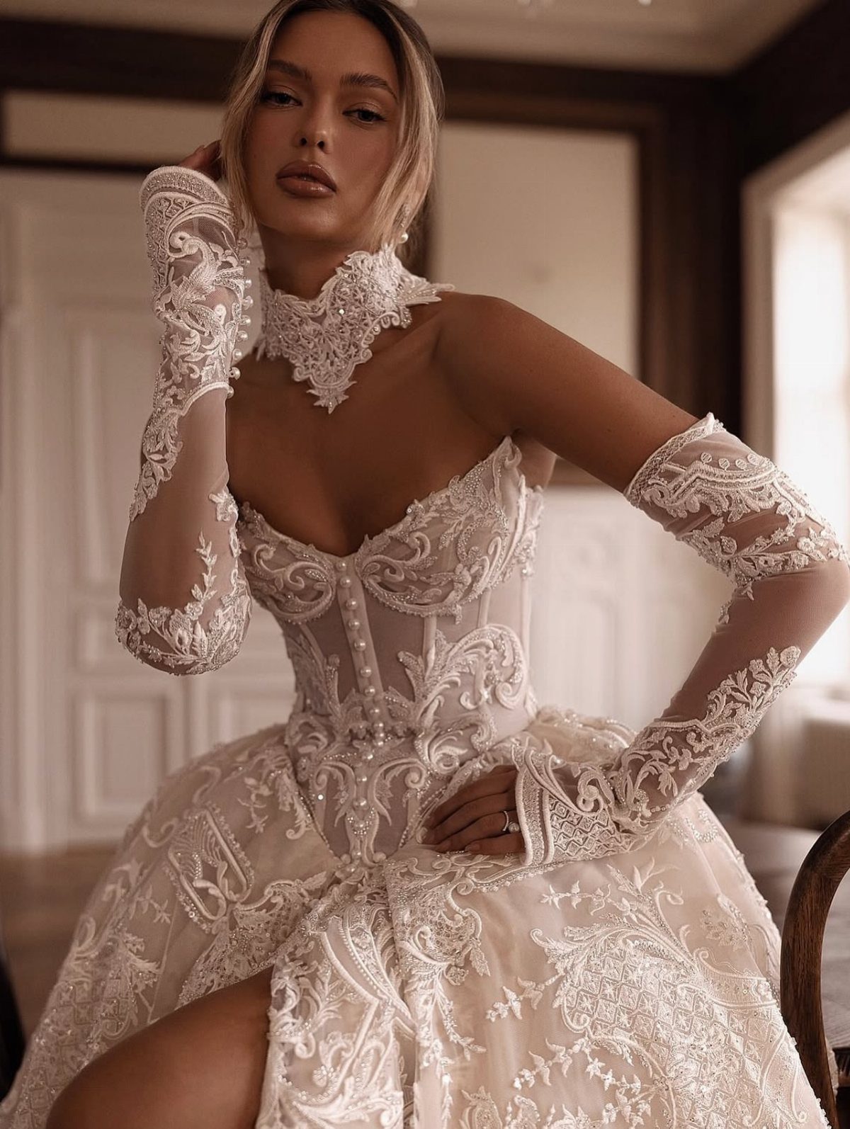 Woman in a champagne lace wedding gown with a beaded corset and lace gloves.