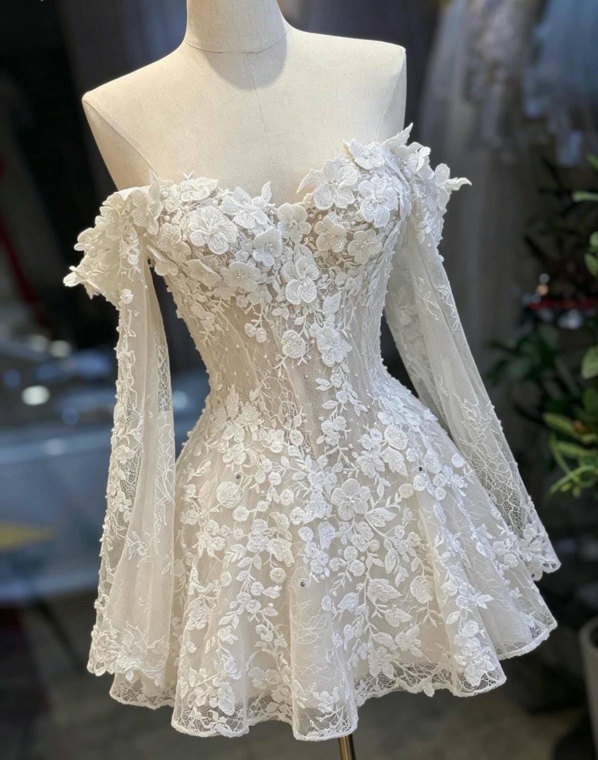 White lace corset mini dress with long sleeves on a bridal mannequin.