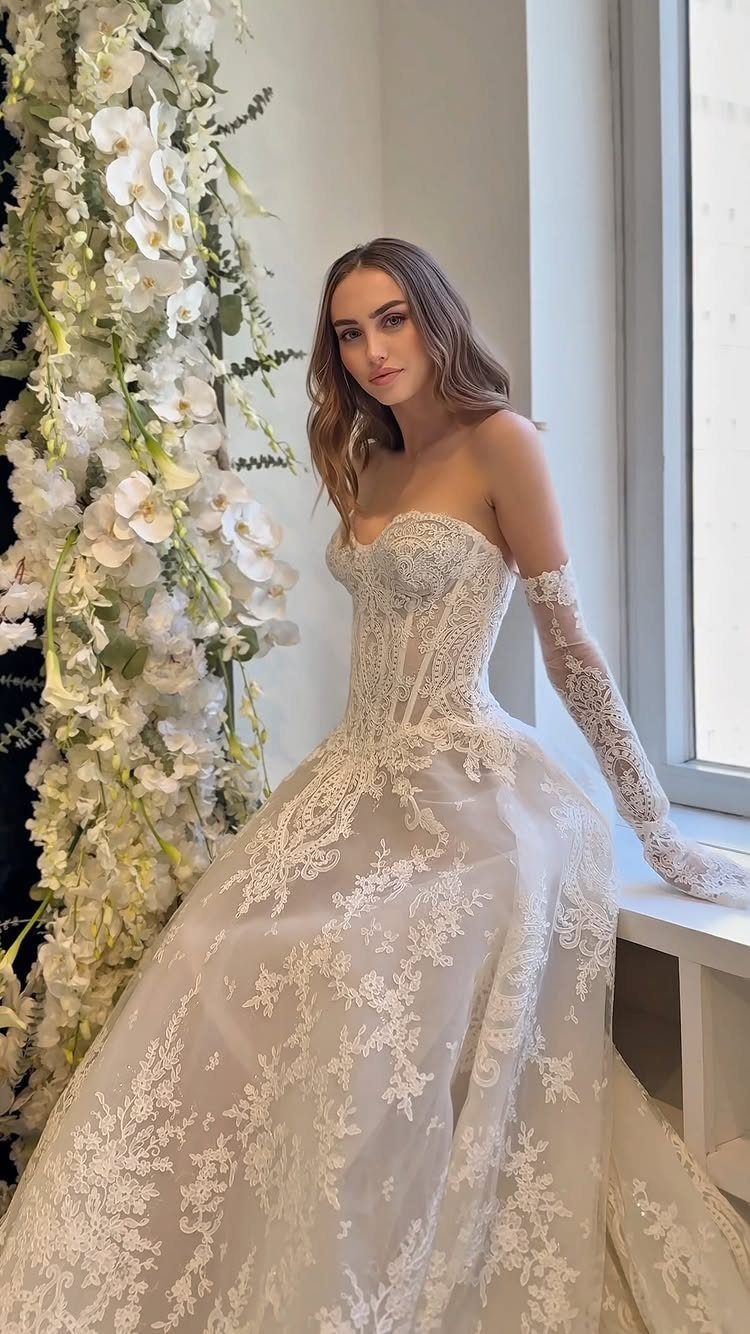 Woman in a strapless white lace wedding gown with a corset bodice and gloves.
