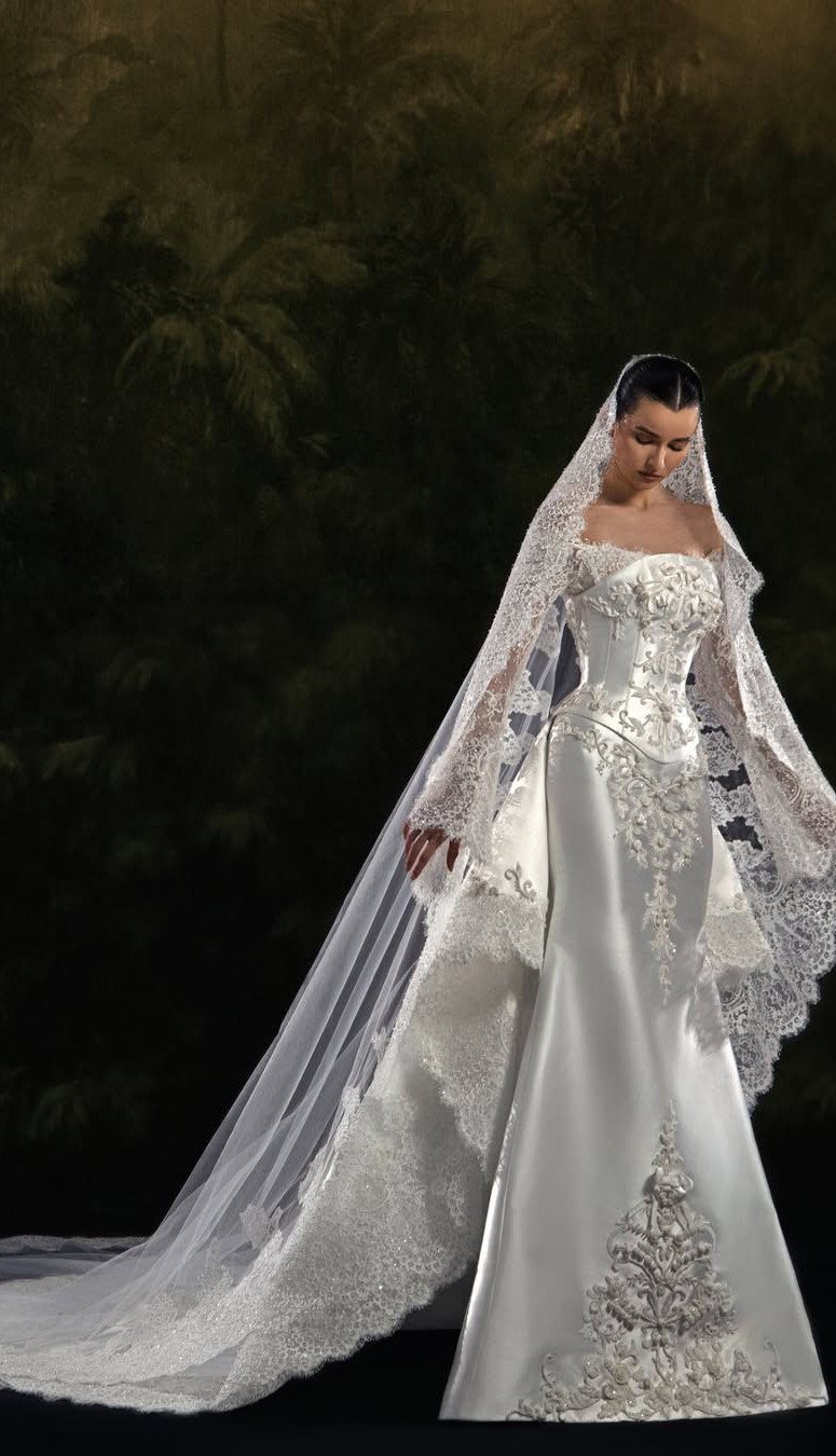 Woman in a white strapless lace wedding dress with a corset and long veil.