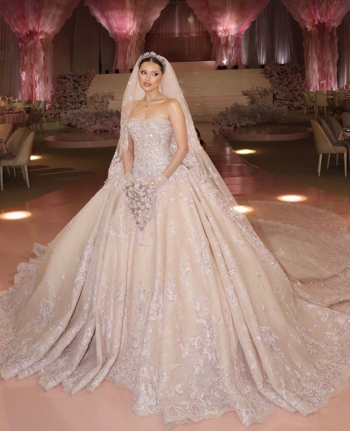 Woman in a powder-pink lace wedding gown with a strapless corset and veil.