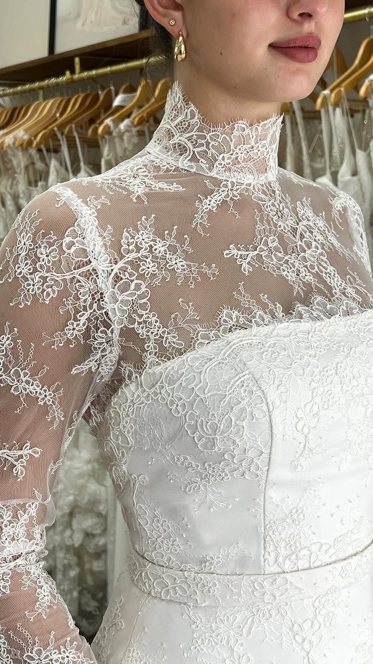 White strapless lace wedding gown paired with a high-neck sheer lace bolero jacket.