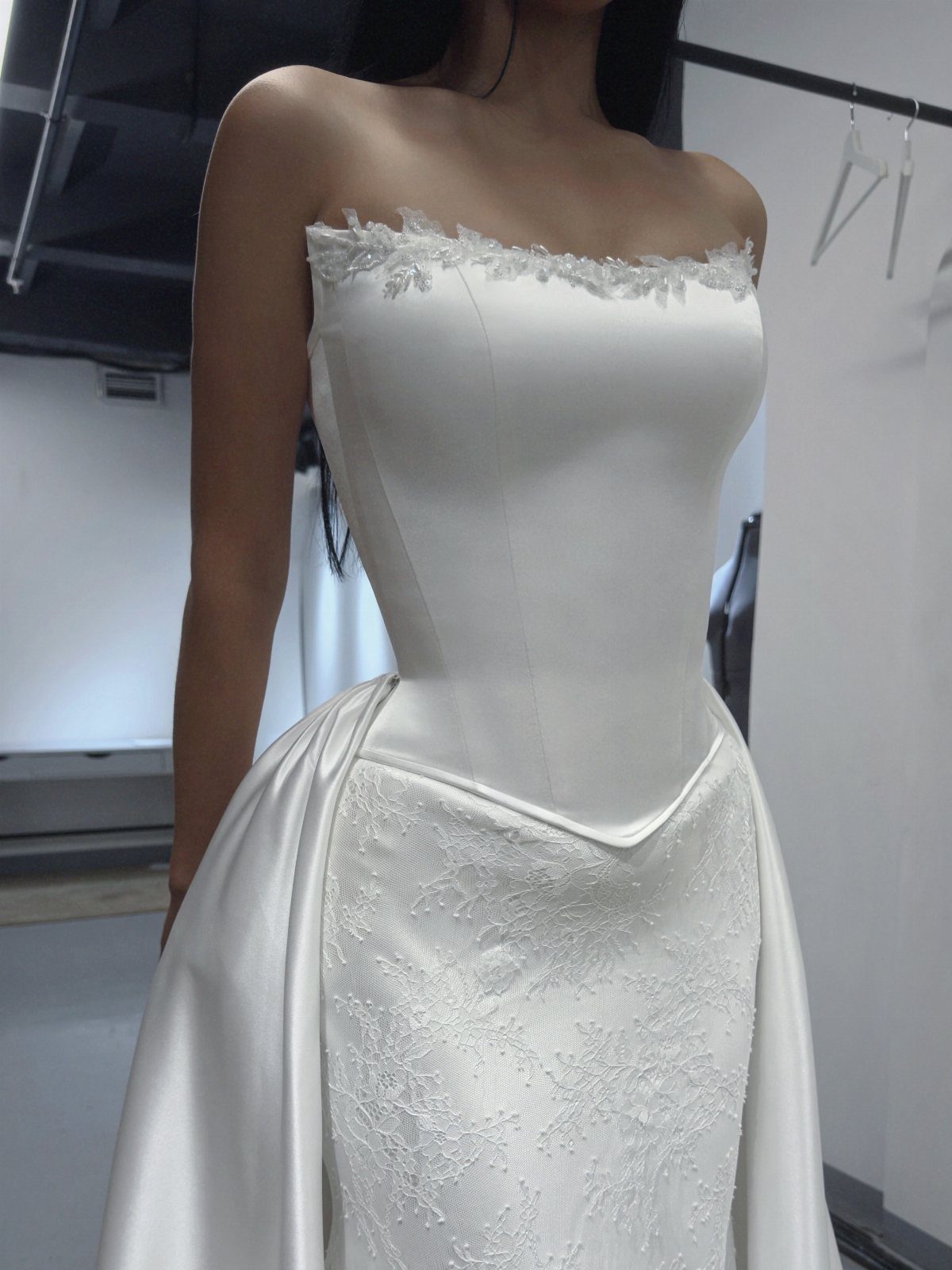 Strapless white satin corset wedding gown with a lace skirt and pointed waistline.