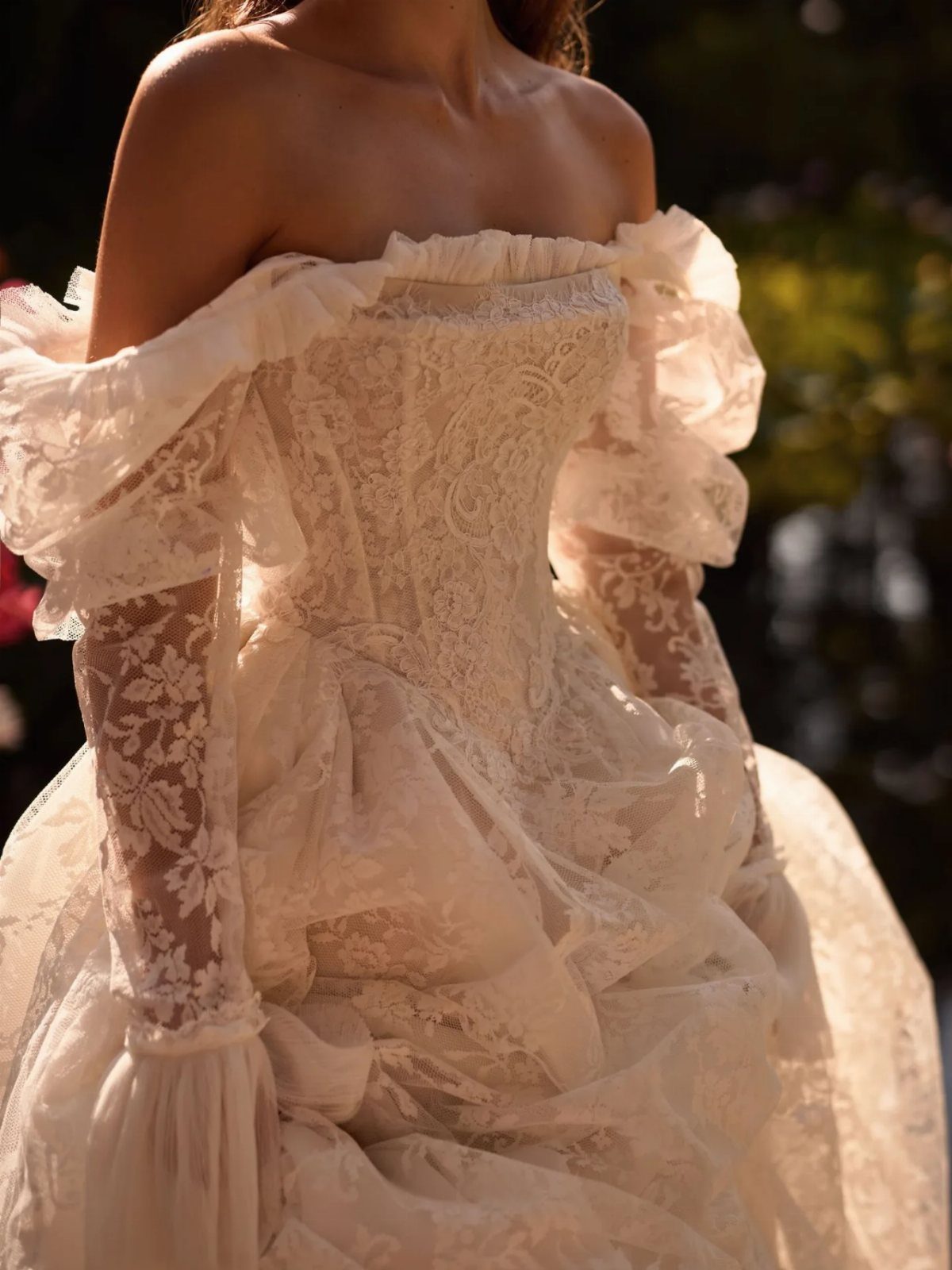 White lace wedding gown with a structured corset bodice and off-the-shoulder sleeves.